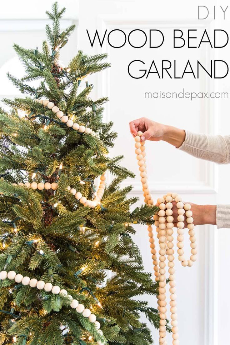 a christmas tree with beads hanging from it's branches and a person holding the bead