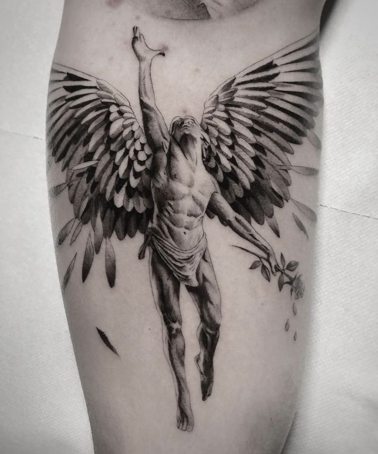 a man with an angel tattoo on his arm and leg, holding the cross above his head