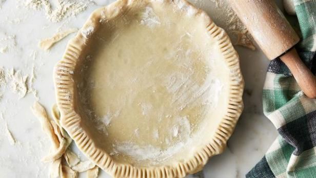 an uncooked pie sitting on top of a table next to utensils