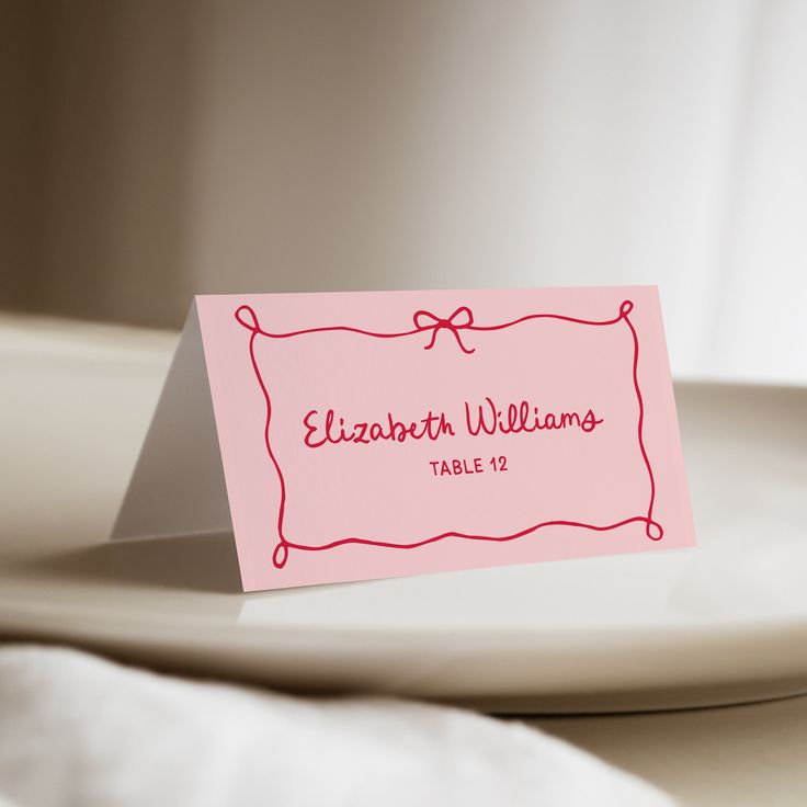 a pink place card sitting on top of a white plate