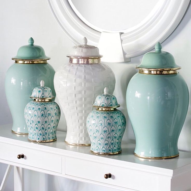 three blue and white vases sitting on top of a table next to a mirror