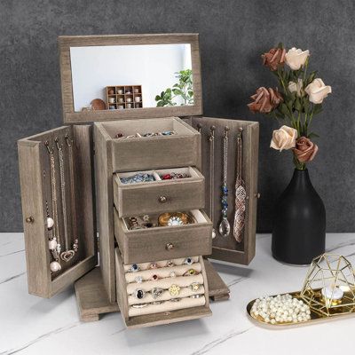 an open jewelry box sitting on top of a table next to a vase with flowers