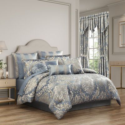 a bed in a bedroom with blue and white comforter set on top of it