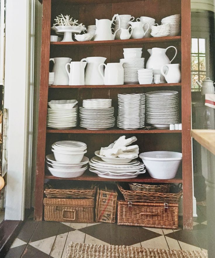 a wooden shelf filled with lots of white dishes