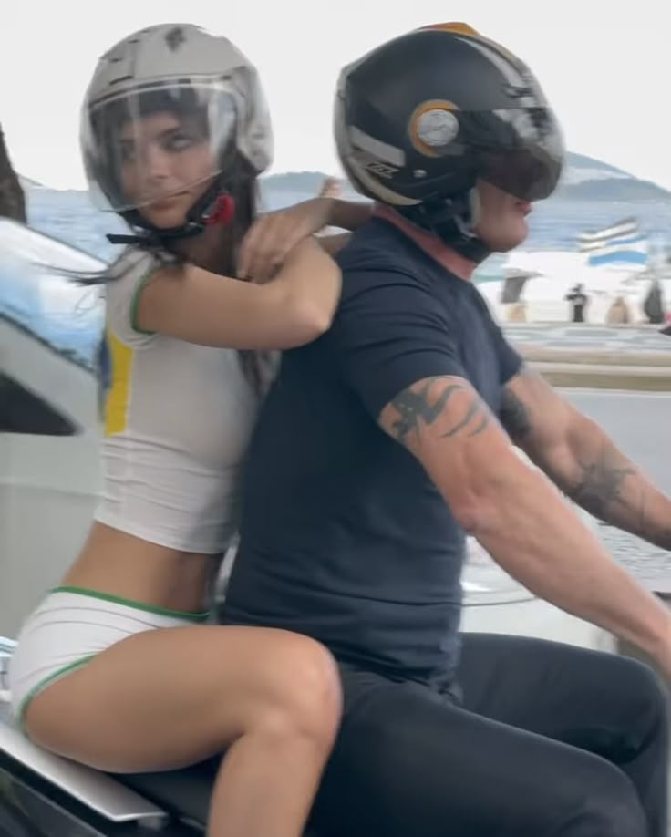 a man riding on the back of a motorcycle next to a woman wearing a helmet