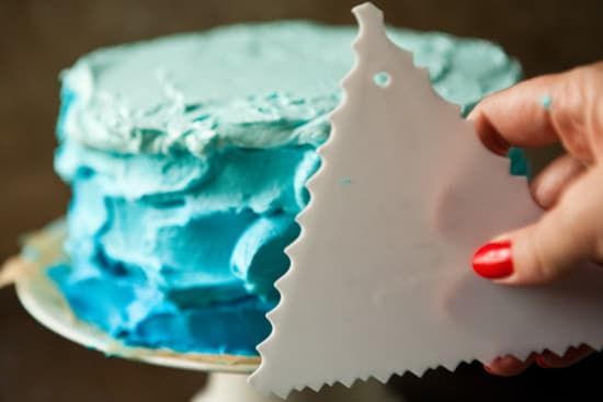 a person holding a piece of cake with blue frosting and a christmas tree decoration on it