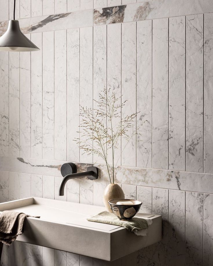 a bathroom sink sitting under a light fixture next to a wall mounted faucet