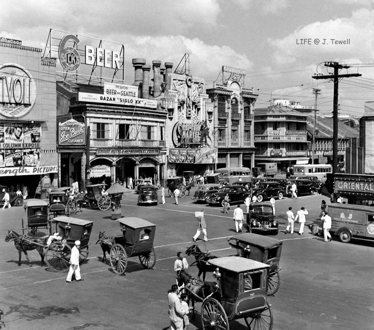 an old black and white photo of people on the street with horse drawn carriages in front of buildings