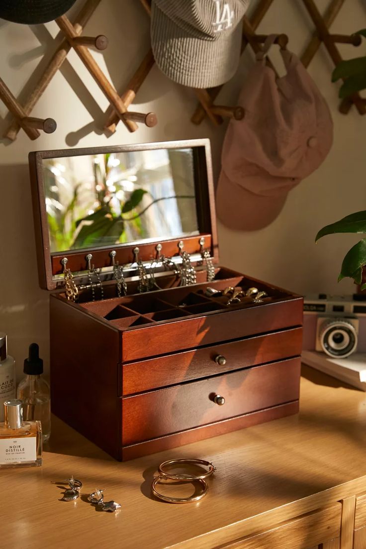 an open jewelry box sitting on top of a wooden table next to a plant and other items