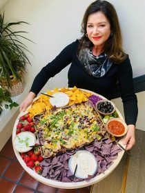 a woman holding a platter full of food