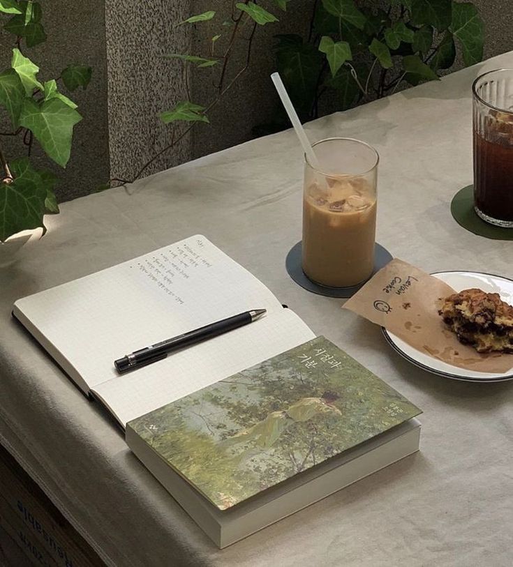 a table topped with an open book next to a plate of food and a drink