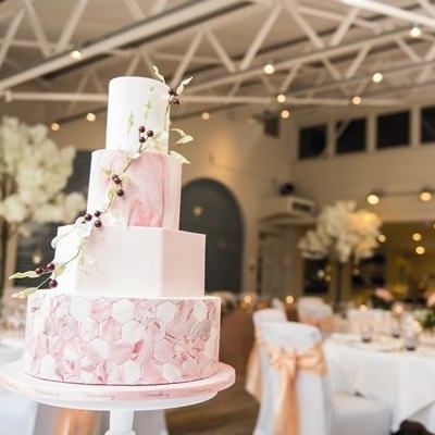 a pink and white wedding cake sitting on top of a table in a banquet room