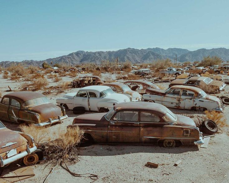 old cars are parked in the desert with mountains in the background