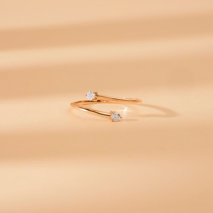 two diamond rings sitting on top of each other in front of a beige background,