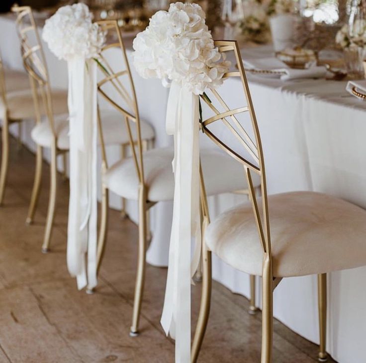 a row of chairs with white flowers on them and bows tied to the back of each chair