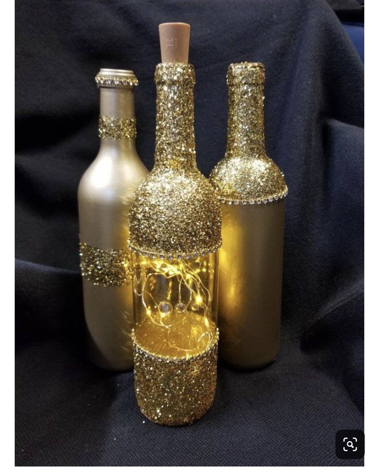 three bottles with gold glitter on them sitting next to each other