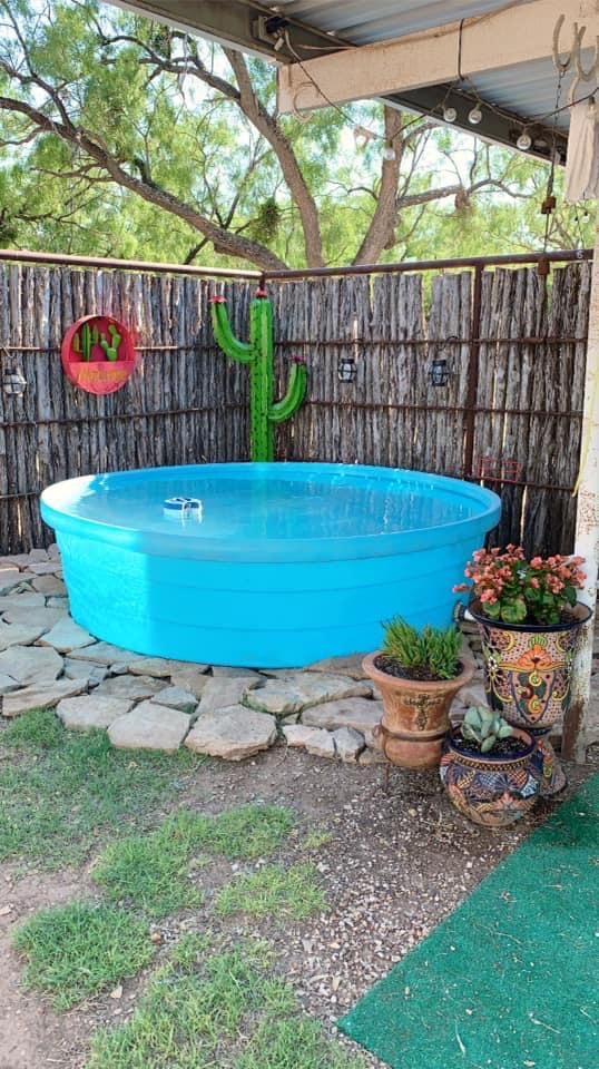 an above ground pool surrounded by plants and rocks