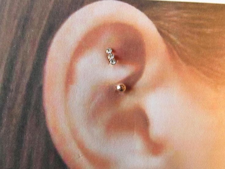 a woman's ear with a small diamond in the middle and a tiny heart on it