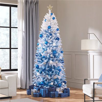 a blue and white christmas tree in a living room with presents on the floor next to it