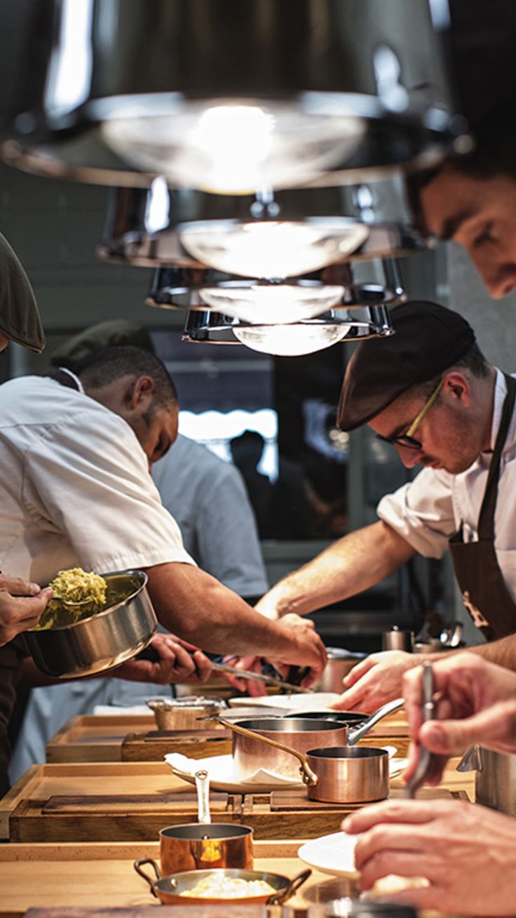 several chefs are preparing food in a kitchen