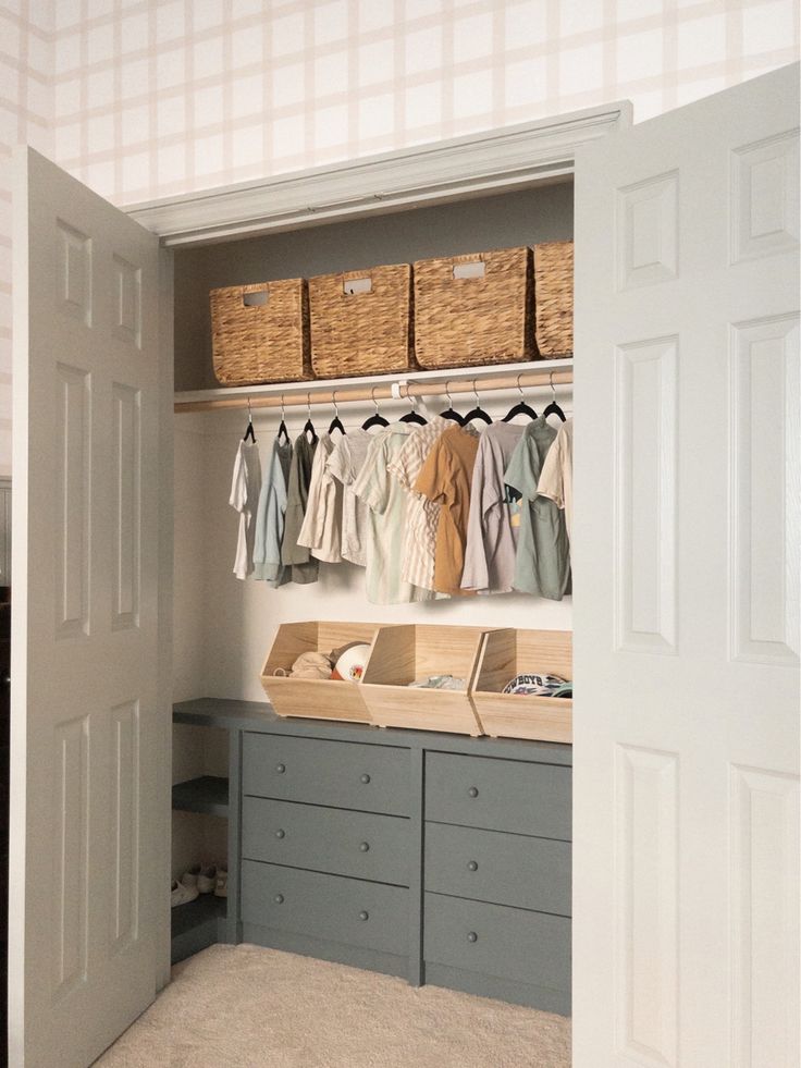 an organized closet with baskets and clothes hanging on the wall, next to two doors