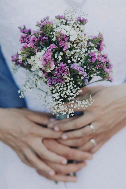 a bouquet of flowers in the hands of a bride and groom on their wedding day