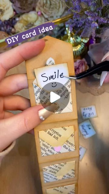 someone is holding a small piece of paper with the word smile on it and there are flowers in the background