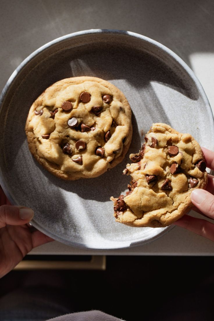 two chocolate chip cookies sitting on top of a metal plate