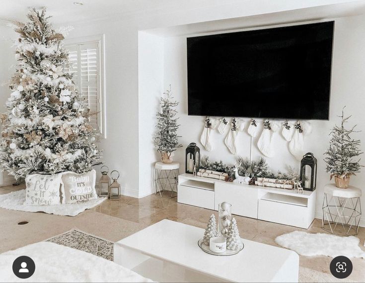 a living room decorated for christmas with white furniture and a large flat screen tv mounted on the wall