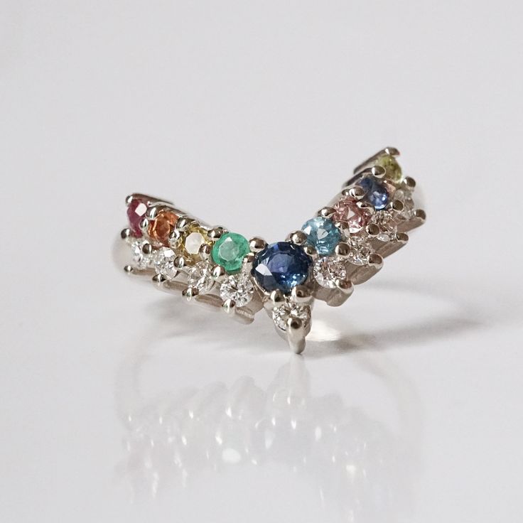 a multicolored diamond ring sits on a white surface