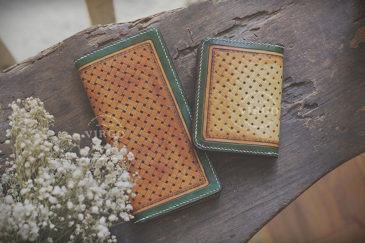 two leather wallets sitting on top of a wooden table