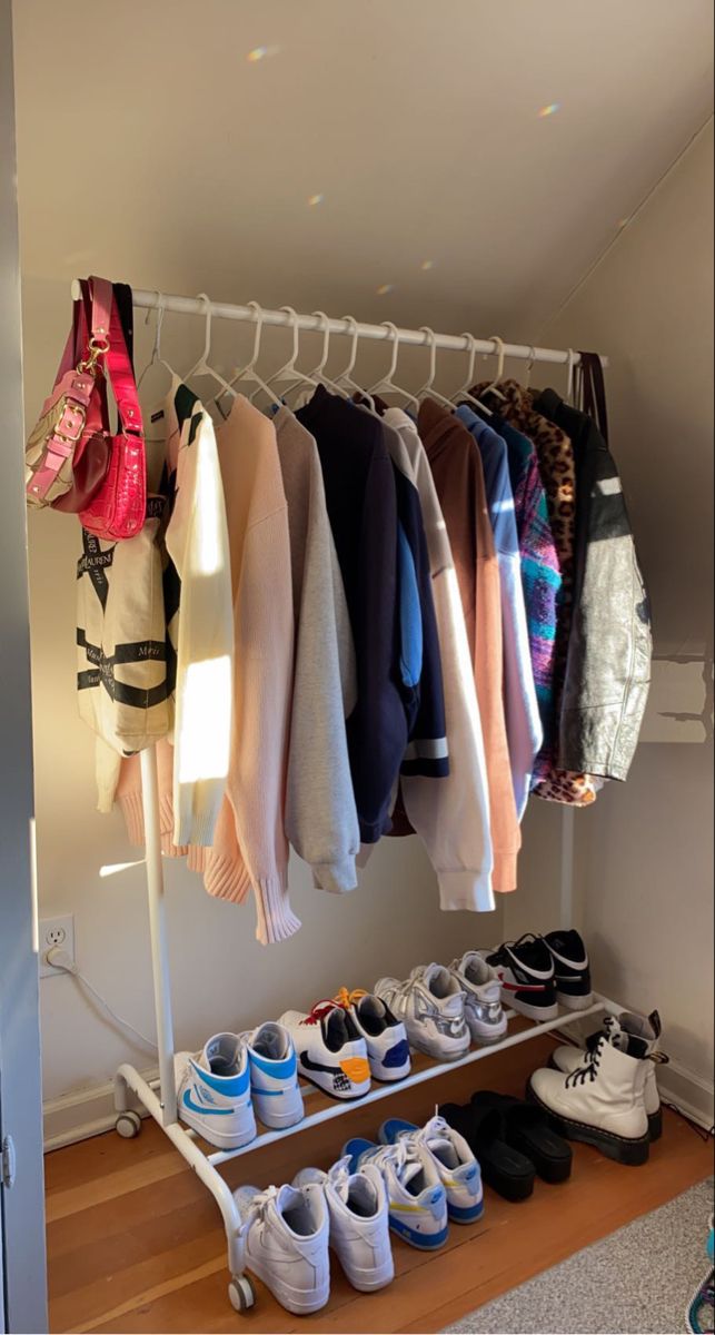 a rack with shoes and sweaters hanging from it's sides in a room