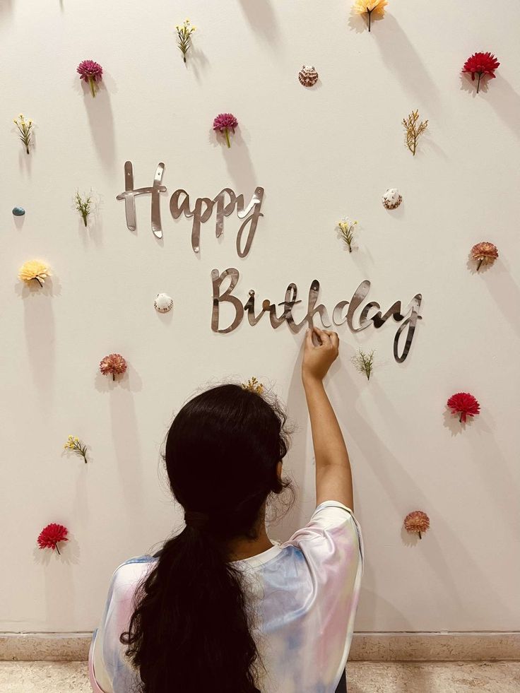 a woman writing happy birthday on the wall