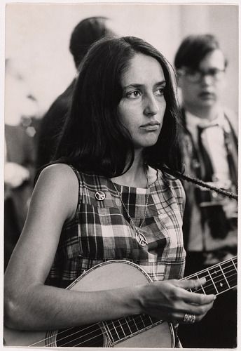 a woman holding a guitar while standing next to a man