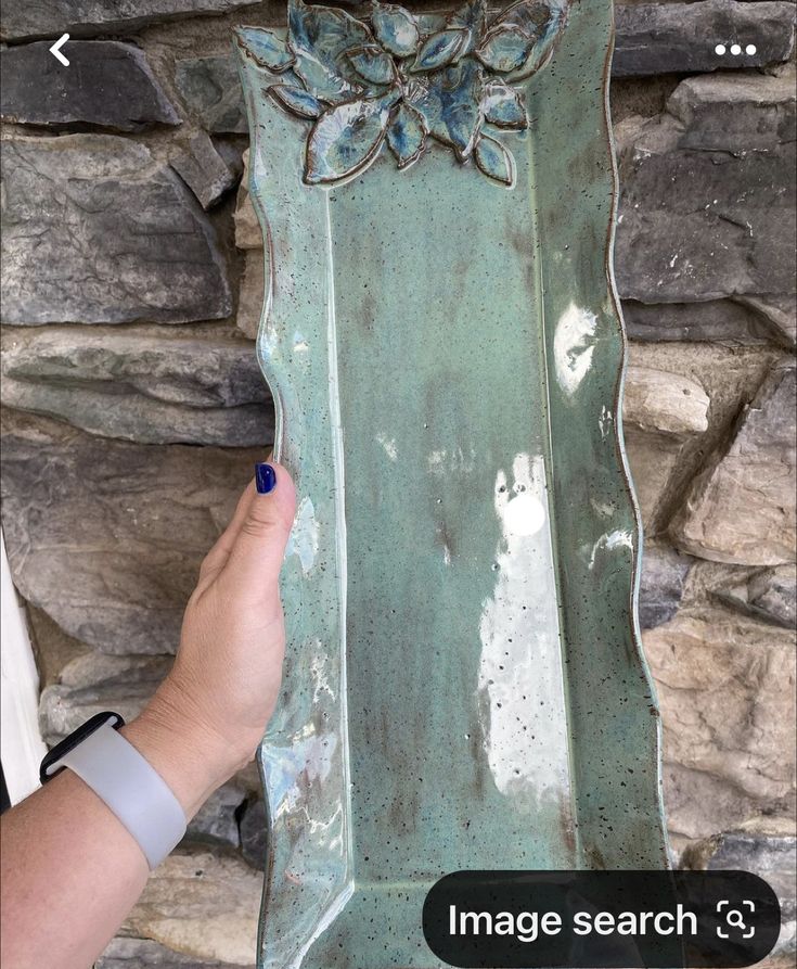 a person is holding up a large metal object with flowers on it's side