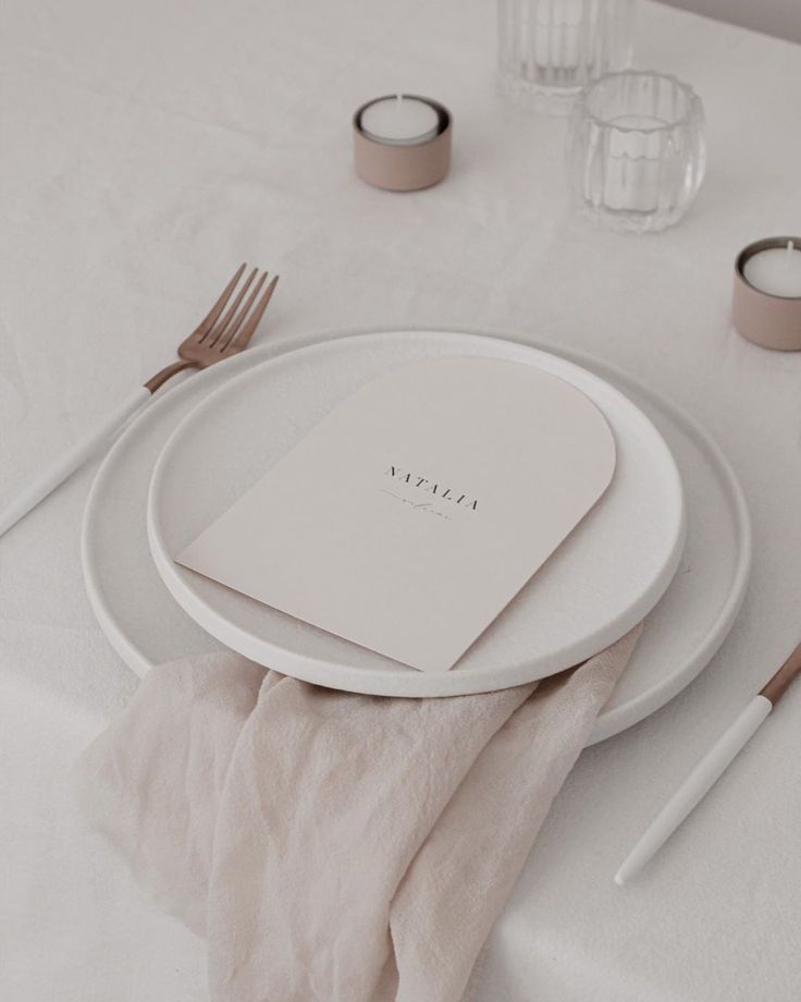 a white table setting with napkins, silverware and place settings on the table