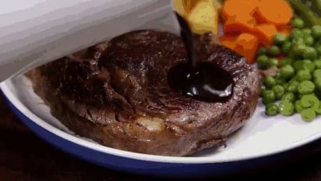 a plate with steak, peas and carrots on it next to a glass of wine