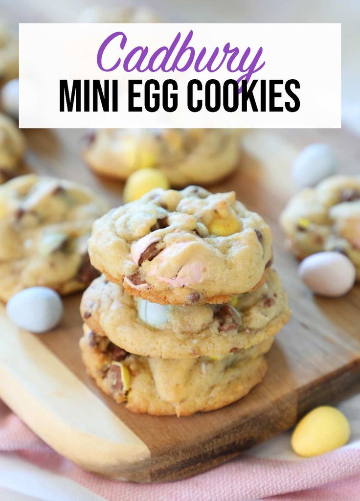 cadbury mini egg cookies are stacked on a wooden board with candy candies around them