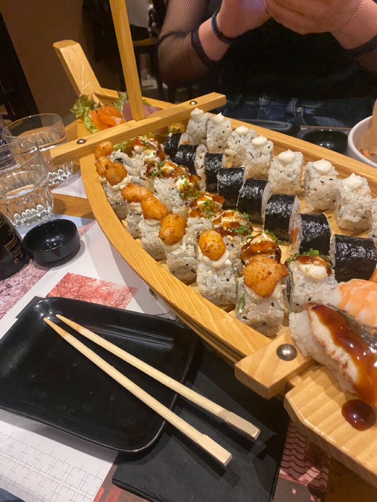 sushi in a boat with chopsticks and sauce on the side at a restaurant