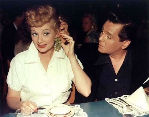 a woman sitting at a table talking on a cell phone next to a man in a black shirt