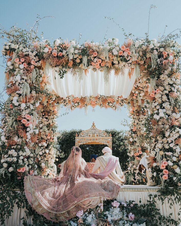 the bride and groom are sitting under an archway decorated with flowers