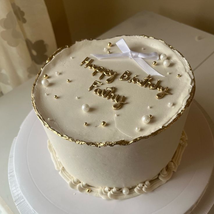 a white and gold birthday cake sitting on top of a table