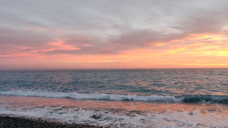 the sun is setting over the ocean with waves coming in