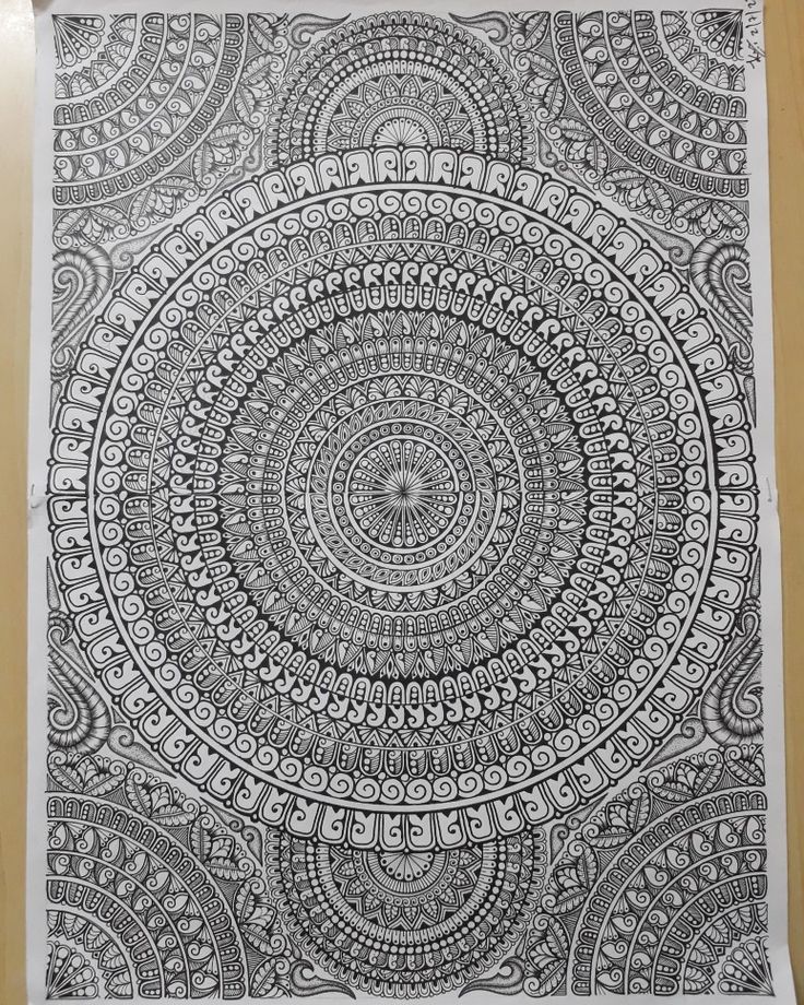 a black and white drawing on paper with an intricate circular design in the middle, surrounded by smaller circles