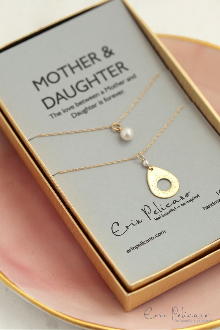 a mother and daughter necklace in a gift box on a pink plate with gold lettering