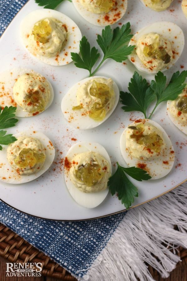 deviled eggs with mustard and parsley on a white plate, ready to be eaten