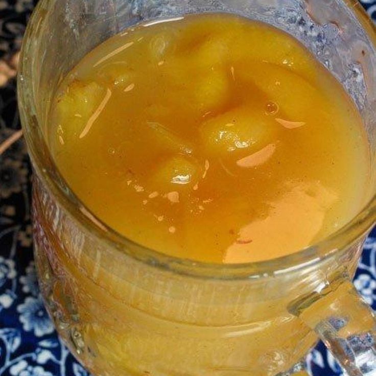 a pitcher filled with liquid sitting on top of a blue and white table cloth next to an orange slice