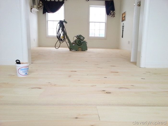 a room with hard wood floors and two windows