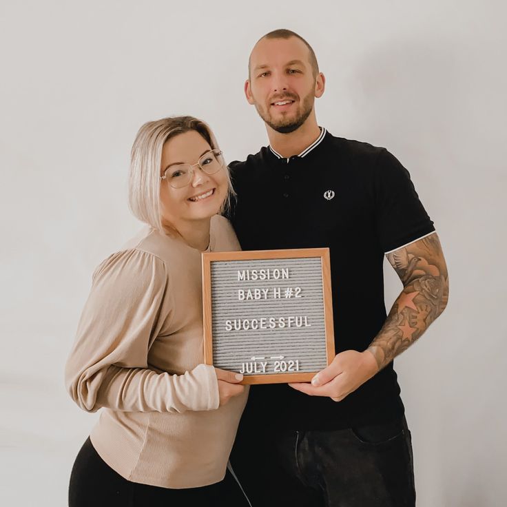 a man and woman posing for a photo with a plaque that says happy baby's first successful birthday