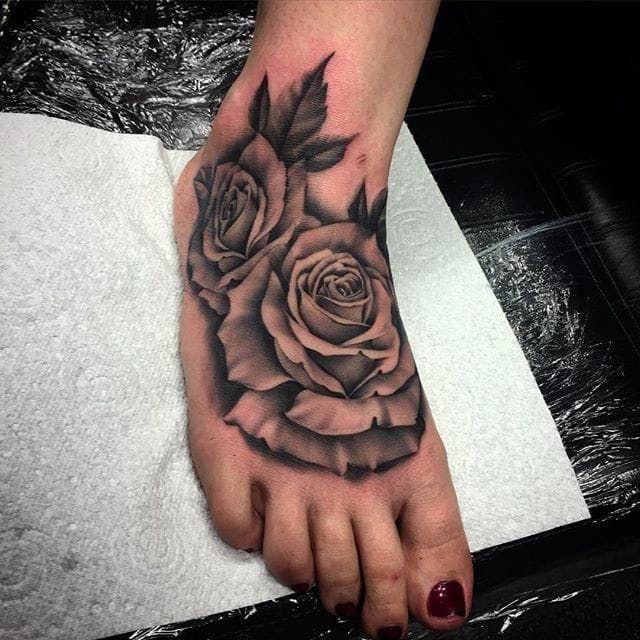 a black and white rose tattoo on the foot